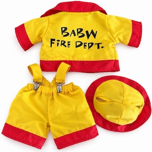 May include: A yellow and red firefighter outfit for a stuffed animal, including a short-sleeved jacket with the text BABW FIRE DEPT. printed on the back, matching shorts with attached suspenders and metal clips, and a round yellow and red hat.