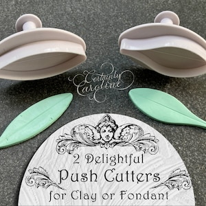 May include: Two white plastic leaf-shaped cookie cutters with a green leaf-shaped fondant cutter and a white background with the text "2 Delightful Push Cutters for Clay or Fondant".