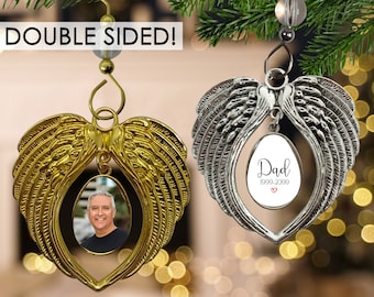 May include: Double-sided angel wing Christmas ornament with a photo insert on one side and a personalized inscription on the other. The inscription reads "Dad 1990-2000" with a small red heart.