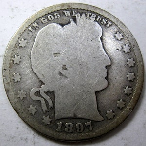 May include: A silver coin from 1897, featuring a profile of a woman and the inscription "IN GOD WE TRUST." The coin's edge is decorated with stars. The year "1897" is visible at the bottom of the coin.