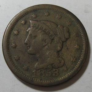 May include: A copper-colored coin from 1853, featuring a profile of a woman wearing a coronet, surrounded by stars. The coin has a detailed edge and is slightly worn, showing signs of age and use. The year 1853 is clearly visible.