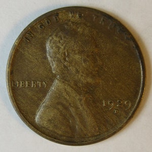 Könnte beinhalten: Eine bronzefarbene Lincoln-Münze von 1929. Die Vorderseite zeigt ein Profil von Abraham Lincoln, das Wort "LIBERTY" und den Satz "IN GOD WE TRUST". Das Jahr "1929" ist sichtbar.
