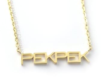 Op de afbeelding: Gouden ketting met de naam "PEKPEK" gespeld in blokletters.