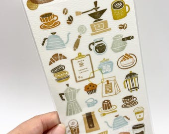 May include: A clear plastic sheet of Hanko Seal stickers featuring various coffee-themed illustrations in muted earth tones. The designs include coffee cups, a French press, a moka pot, a coffee grinder, a kettle, a croissant, a slice of cake, and coffee beans.