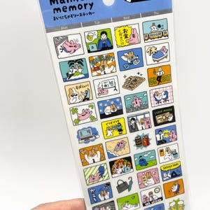 Könnte beinhalten: Ein rechteckiger Bogen mit Mainichi memory Aufklebern, der ein Raster aus bunten Cartoon-Illustrationen von Hasen in verschiedenen Alltagssituationen zeigt, darunter Büroarbeit, Freizeit und Reisen, mit japanischem Text und englischen Phrasen wie ENERGY und GREAT.