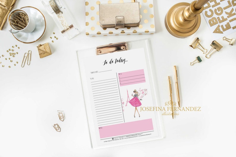 May include: A white clipboard with a pink to-do list titled "To do Today..." with a pink and white striped dress illustration of a woman standing in front of the Eiffel Tower. The clipboard has a gold clip.