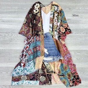 Puede incluir: Un kimono largo multicolor con un dise&ntilde;o de patchwork. El kimono tiene una variedad de patrones florales y geom&eacute;tricos en tonos de rojo, azul, verde, amarillo y marr&oacute;n. La palabra "Mint" est&aacute; escrita en texto blanco sobre un fondo blanco en la esquina superior derecha de la imagen.