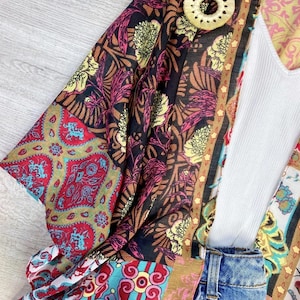Puede incluir: Un kimono colorido con un patr&oacute;n floral y una parte superior blanca debajo. El kimono tiene un patr&oacute;n marr&oacute;n, rojo, azul y amarillo.