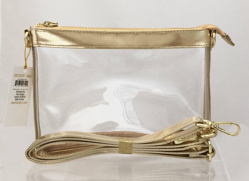 Puede incluir: Un bolso cruzado transparente con cremallera, ribete y correa dorados. El bolso tiene forma rectangular e incluye una correa desmontable. Una etiqueta est&aacute; adherida al bolso. Medidas: aproximadamente 20 cm x 15 cm x 6 cm.