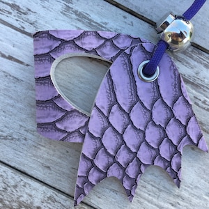 May include: A purple leather key chain with a textured snake skin pattern. The key chain has a metal ring and a metal bead.