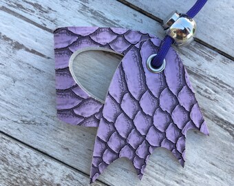 May include: A purple leather key chain with a textured snake skin pattern. The key chain has a metal ring and a metal bead.