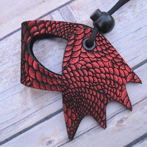 May include: Red leather dragon claw keychain with a black cord and a black toggle clasp.