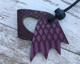 May include: Purple leather key chain with a dragon wing design and a black cord with a black bead.