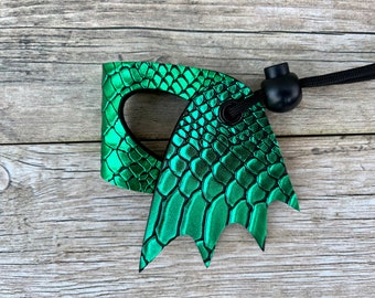 May include: Green dragon-shaped leather key chain with a black cord and a black toggle. The leather has a scaly texture.