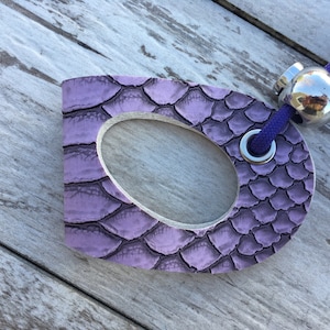 May include: A purple leather key chain with a metal ring and a silver ball charm. The leather has a snakeskin pattern.