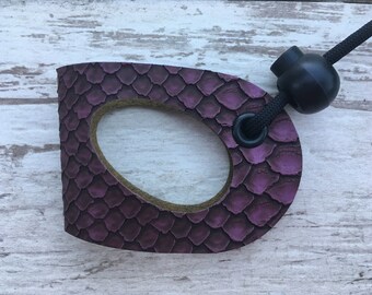 May include: A purple leather dog leash handle with a black cord and a black toggle. The handle has a snakeskin pattern.