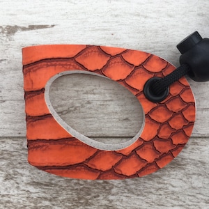 May include: Orange leather dog leash handle with a black textured surface and a black cord with a black bead.