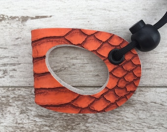 May include: Orange leather dog leash handle with a black textured surface and a black cord with a black bead.