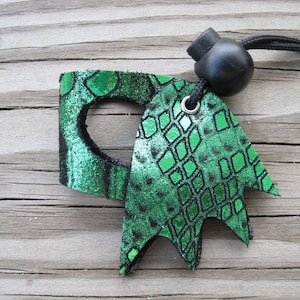 May include: A green leather key chain with a snake skin pattern and a black cord with a black bead.