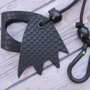May include: Black leather key chain with a textured snake skin pattern, a black carabiner clip, and a black cord with two black beads.