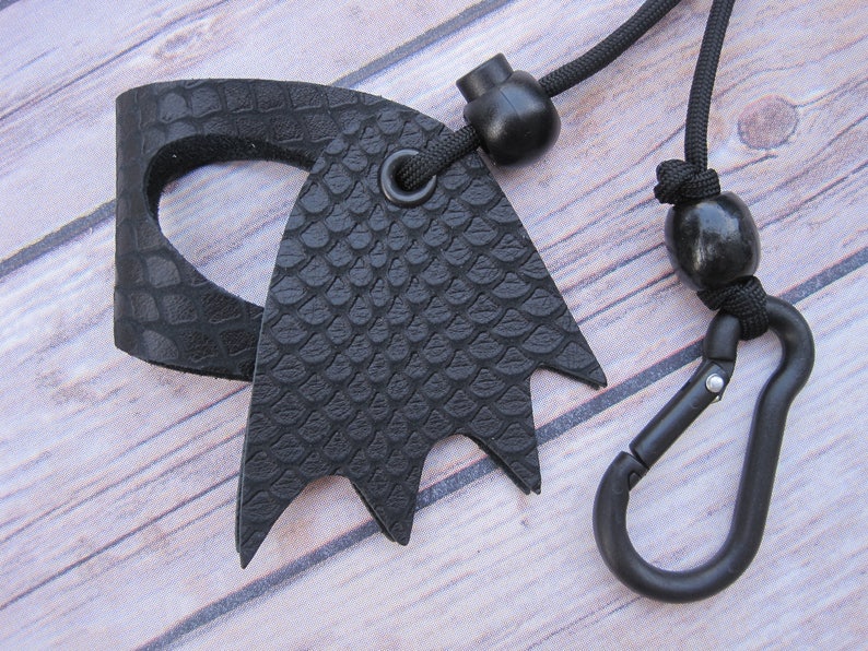 May include: Black leather key chain with a textured snake skin pattern, a black carabiner clip, and a black cord with two black beads.