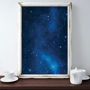 Pu&ograve; includere: Un'immagine incorniciata bianca con uno sfondo blu scuro e stelle bianche. L'immagine &egrave; appoggiata su una superficie in legno marrone scuro.