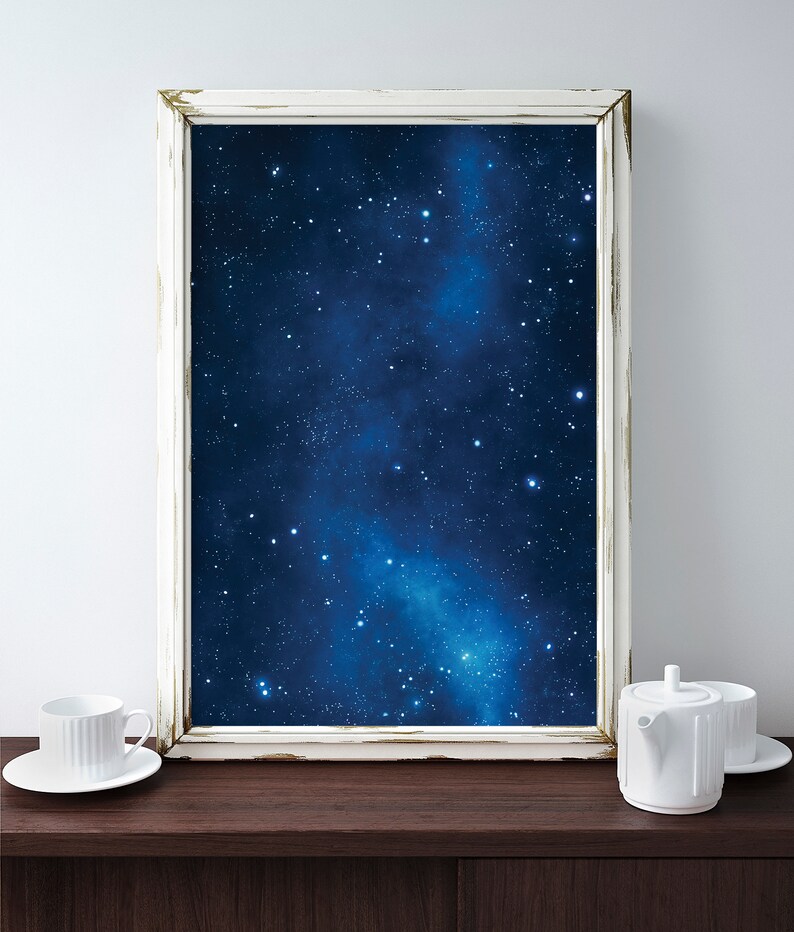 Pu&ograve; includere: Un'immagine incorniciata bianca con uno sfondo blu scuro e stelle bianche. L'immagine &egrave; appoggiata su una superficie in legno marrone scuro.