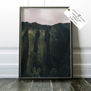 May include: A framed photograph of a lush green mountain range with a waterfall cascading down the side. The sky is a soft pink and purple.