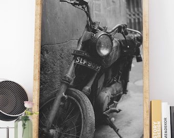 May include: Black and white photograph of a vintage motorcycle with a license plate that reads "SLF 9095". The motorcycle is parked on a street and the front wheel is in focus.