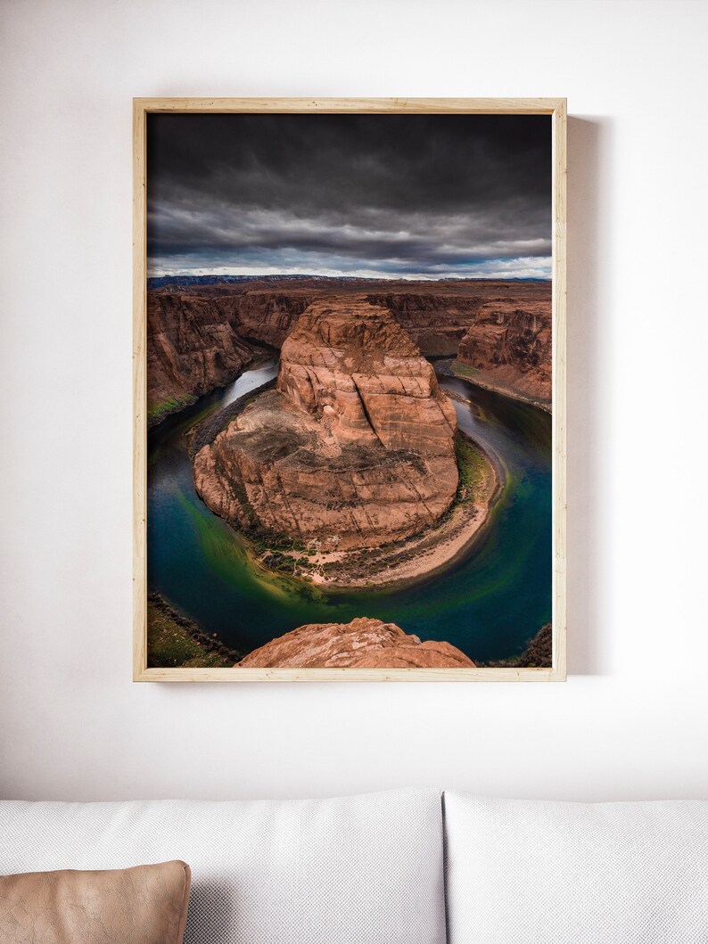 Puede incluir: Fotograf&iacute;a enmarcada de Horseshoe Bend, Arizona. La imagen captura la ic&oacute;nica curva en forma de herradura del r&iacute;o Colorado, con formaciones rocosas rojas y un cielo oscuro y nublado. El agua es de un azul verdoso profundo.