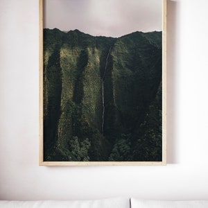 May include: A framed photograph of a lush green mountain range with a waterfall cascading down the side. The sky is a soft, light pink.
