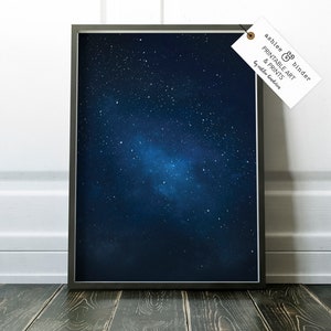 K&ouml;nnte beinhalten: Ein gerahmter Druck eines dunkelblauen Nachthimmels mit einem Haufen wei&szlig;er Sterne und einem schwachen Nebel. Der Druck ist in einem schwarzen Rahmen und hat ein wei&szlig;es Etikett mit dem Text "Ashlee & Binder Printable Art & Prints by Ashlee Binder".