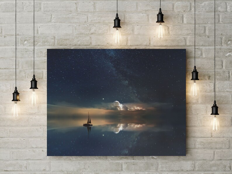 May include: A canvas print of a sailboat on a calm body of water with a starry night sky and a reflection of the stars in the water.