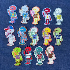 May include: A collection of fourteen embroidered skeleton patches in various colours, each making a peace sign. Several skeletons wear shirts with text including "DEAD 4EVER", "GOOSE 4EVER", "EGGY 4EVER", and "VIVA EL GONZO", while others feature lightning bolt designs.