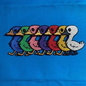 May include: A set of seven embroidered iron-on patches featuring cartoon ducks in a line. The ducks are in different colours: blue, green, pink, purple, red, yellow, and white.