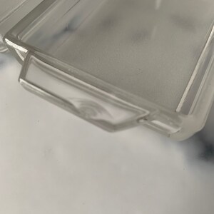 K&ouml;nnte beinhalten: Eine rechteckige Glasschale aus klarem Glas mit erh&ouml;htem Rand und einem Griff an einer Seite. Die Schale ist leer und scheint aus mattiertem Glas zu sein.
