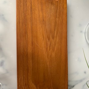 K&ouml;nnte beinhalten: Ein rechteckiges Holztablett mit brauner Beize. Das Tablett hat einen erh&ouml;hten Rand und zwei Aussparungen an jeder Seite.