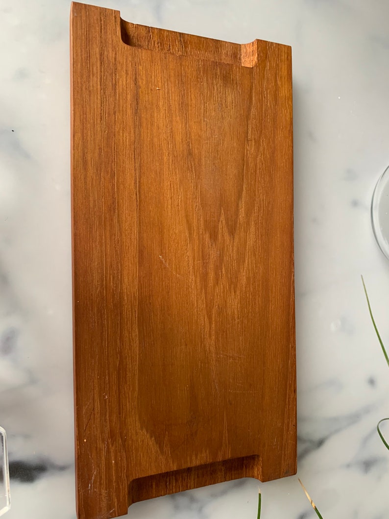 K&ouml;nnte beinhalten: Ein rechteckiges Holztablett mit brauner Beize. Das Tablett hat einen erh&ouml;hten Rand und zwei Aussparungen an jeder Seite.