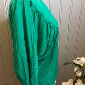 Puede incluir: Una blusa verde de manga larga con cuello en V y tejido texturizado.