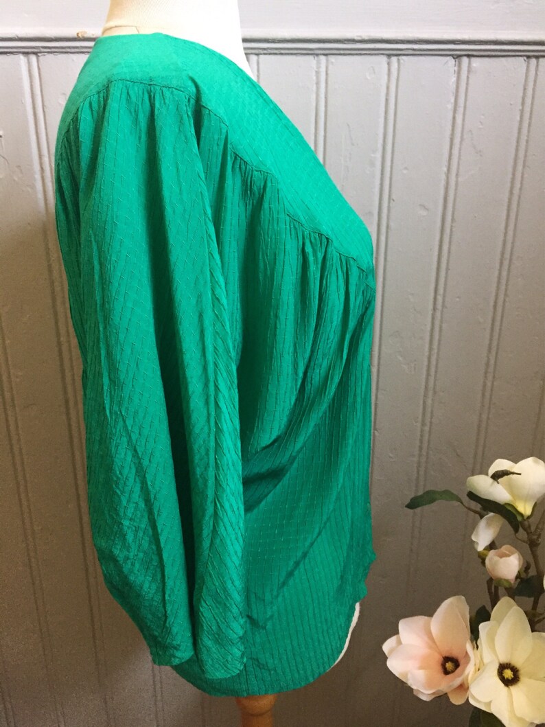 Puede incluir: Una blusa verde de manga larga con cuello en V y tejido texturizado.
