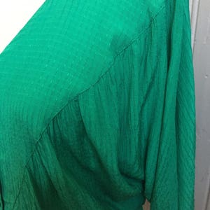 Puede incluir: Una blusa verde de manga larga con textura y cuello en V.