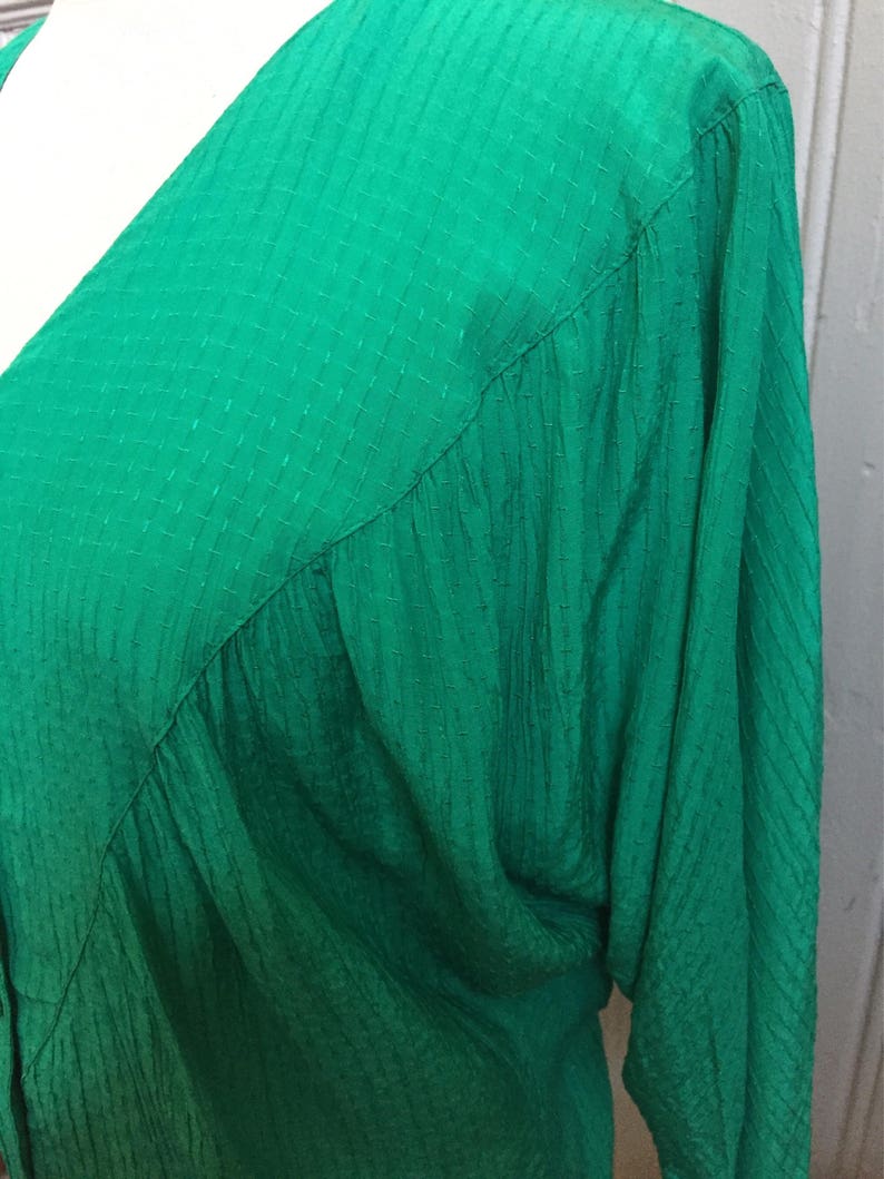Puede incluir: Una blusa verde de manga larga con textura y cuello en V.