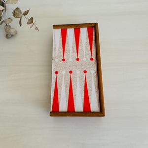 May include: A wooden box with a red and white checkerboard pattern on the lid. The box is closed and has a brown wooden frame.