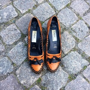 May include: A pair of brown leather loafers with black trim and tassels. The loafers have a woven pattern and the brand name "Gabor" is printed on the inside.