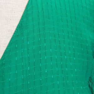 Puede incluir: Primer plano de una tela verde brillante con un patr&oacute;n acolchado texturizado.