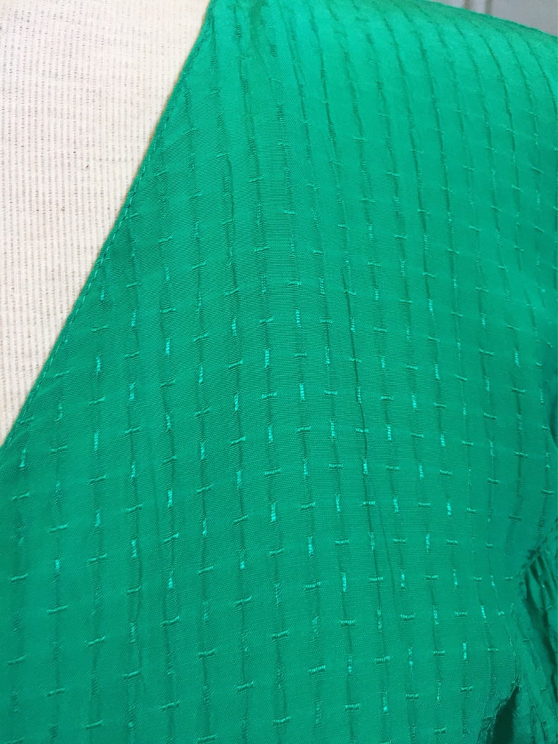 Puede incluir: Primer plano de una tela verde brillante con un patr&oacute;n acolchado texturizado.
