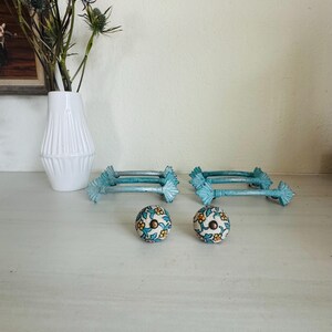 May include: Set of six turquoise ceramic drawer pulls with floral designs. The pulls have a decorative fan-shaped design on each end. Two matching knobs are also included.
