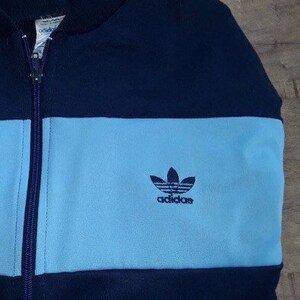 May include: A blue and light blue Adidas zip-up jacket with the Adidas logo on the front.