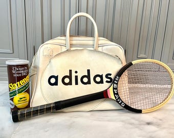 May include: White leather Adidas tennis bag with a tennis racket and a can of Slazenger tennis balls. The bag has the Adidas logo on the front.