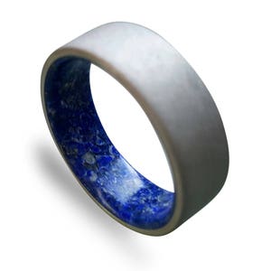 May include: A silver ring with a blue and white inlay. The ring is made of a durable material and has a smooth finish.